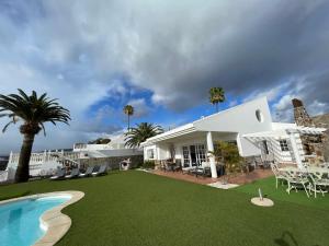 a white house with a lawn and a swimming pool at Casa Alegria in Puerto Rico de Gran Canaria