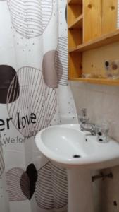a bathroom with a white sink and a shower curtain at Carla Tryana Fernandes Castro in Vila do Porto
