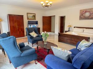 a living room with blue chairs and a bed at Miyanwe Guest House - Waterkloof in Pretoria