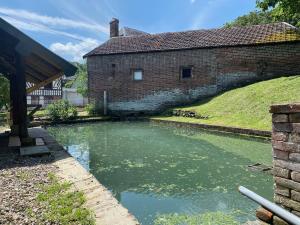 a river in front of a brick building at La Halte de la Hunière - Jardin - Central - Garage in Vimoutiers