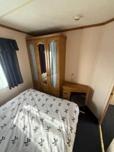 a small bedroom with a bed and a wooden cabinet at Holiday Home Arbroath in Arbroath