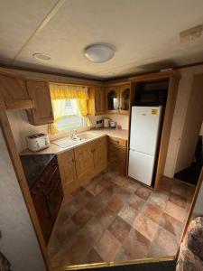a kitchen with wooden cabinets and a white refrigerator at Holiday Home Arbroath in Arbroath +5 photos