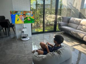 a young boy sitting in a chair playing a video game at Find 777 B&B in Guilin