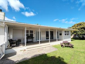 a white house with a picnic table in the yard at Rehutai Beach House in Paihia