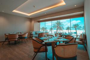 a restaurant with tables and chairs and a view of the beach at Hills HOTEL - فندق هيلز in Al Khobar