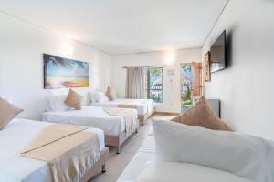 a hotel room with three beds and a couch at Hotel La Fragata Coveñas in Coveñas