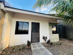a white house with a black door and a palm tree at Akina 2bedroom Transient House in Kabankalan