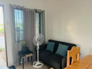a living room with a black couch and a fan at Akina 2bedroom Transient House in Kabankalan