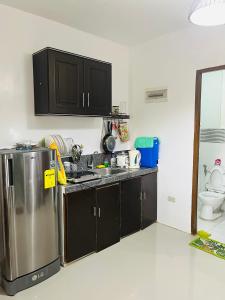 a kitchen with black cabinets and a stainless steel refrigerator at Akina 2bedroom Transient House in Kabankalan +3 photos