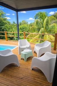 a deck with white chairs and a table and a pool at Kaloukera in Trois-Rivières