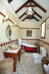 a bathroom with a red tub and a toilet and a sink at House On The Path in Windward Side
