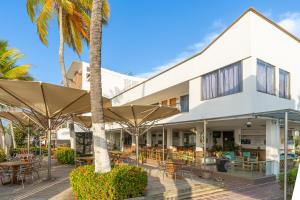 an outdoor patio with tables and umbrellas in front of a building at Hotel La Fragata Coveñas in Coveñas