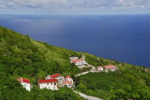 a group of houses on a hill next to the ocean at House On The Path in Windward Side