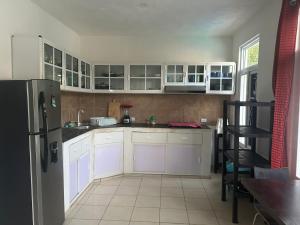 a kitchen with white cabinets and a black refrigerator at La casa de Fercho in Sipacate
