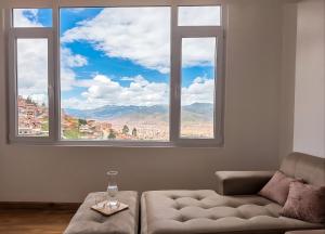 a living room with a couch and three windows at Cusco Nest in Cusco
