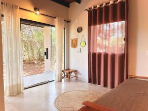 a bedroom with a bed and a large sliding glass door at Claruá Chalés- Loft Caju- Pé direito duplo, 3min de carro do Rio- Conforto e Natureza dentro da cidade in Cavalcante