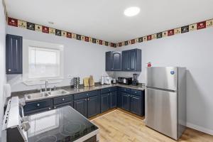 a kitchen with blue cabinets and a stainless steel refrigerator at Modern Niagara Loft with Private Sunset Balcony Duplex in Niagara Falls