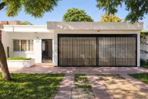 a white house with a black garage door at JACARANDA - Alojamiento vacacional in Godoy Cruz