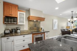 a kitchen with white cabinets and a sink at Star Suite -Luxurious condo with 3 fireplaces, and open Pool! in Canmore