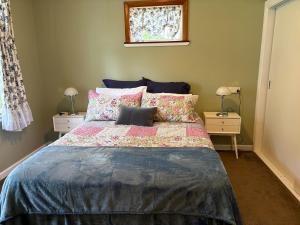 a bedroom with a large bed with pillows at Sanctuary Cottage in Karapiro