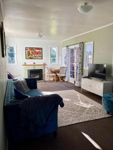 a living room with a blue couch and a table at Sanctuary Cottage in Karapiro
