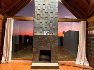 a living room with a stone fireplace with windows at Lazer e descanso em Witmarsum in Palmeira