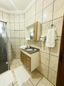a bathroom with a sink and a shower at Apartamento Super Conforto in Naviraí +48 photos