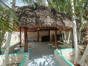 a hut with chairs and a table and palm trees at Turquesa Bacalar Centro in Bacalar