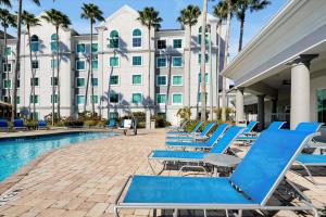 a row of blue lounge chairs next to a swimming pool at Pool View DisneyUniversalFree ShuttleParking in Orlando