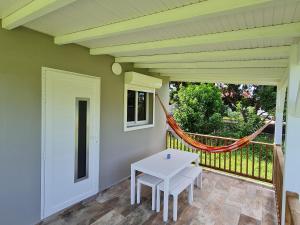 a porch with a white table and a hammock at Canopée Créole in Petit-Canal