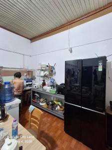 a person standing in a kitchen with a black refrigerator at Lương Y Trần Thúy Liên in Bảo Lộc