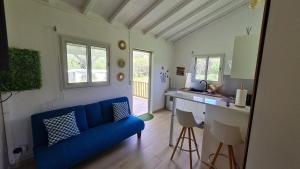a living room with a blue couch and a kitchen at Canopée Créole in Petit-Canal