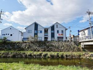 a building on a hill next to a river at ゲストハウス豆まめ - Guesthouse Mamemame in Matsumoto