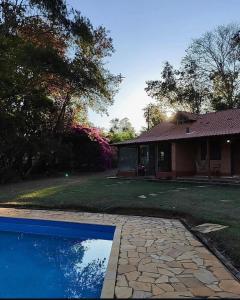 a house with a swimming pool in front of a house at Pousada Árvore Centenária in São Thomé das Letras