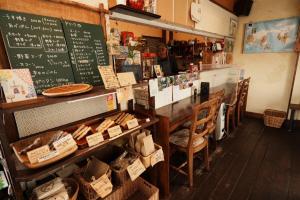 a person sitting at a counter in a restaurant with a chalkboard at ゲストハウス豆まめ - Guesthouse Mamemame in Matsumoto