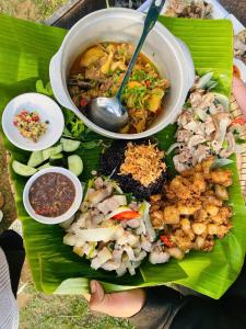 a person holding a plate of food on a banana leaf at May Farm in Hương Hóa