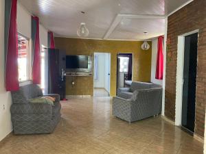 a living room with two chairs and a television at Casa com Piscina em Prado Bahia in Prado