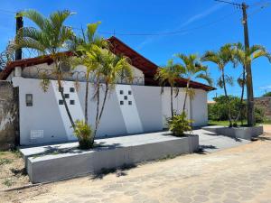 a white house with palm trees in front of it at Casa com Piscina em Prado Bahia in Prado