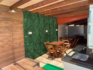 a kitchen with a green wall with tables and chairs at Casa com Piscina em Prado Bahia in Prado