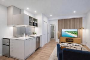 a kitchen with white cabinets and a living room at Fitzgerald Focus - Your 1BR Urban Oasis in Christchurch +8 photos
