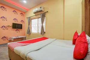 a bedroom with a large bed with red pillows at Super Hotel O Priyal Amrit Sagar in Rourkela