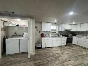 a kitchen with white cabinets and a wooden floor at Cozy Apt in Downtown Logan in Logan