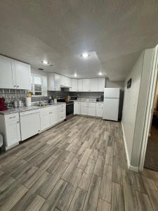 a large kitchen with white cabinets and wooden floors at Cozy Apt in Downtown Logan in Logan