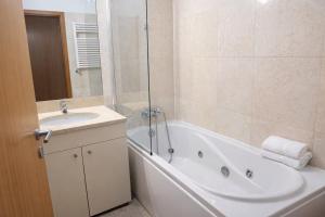 a bathroom with a white tub and a sink at Free Wave Rooms in Maia +10 photos