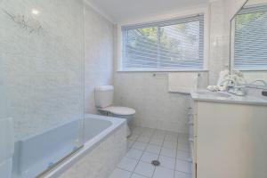 a bathroom with a tub and a toilet and a sink at Billie's on Smiths in Smiths Lake +23 photos