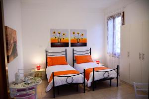 two beds in a bedroom with orange and white at Casa Bianca in Mestre