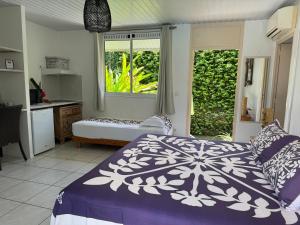 a bedroom with a bed and a kitchen and a window at Relais Fenua in Punaauia