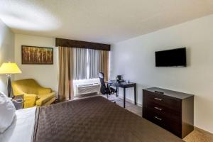 a hotel room with a bed and a desk and a television at Clarion Inn near McAllen Airport in McAllen
