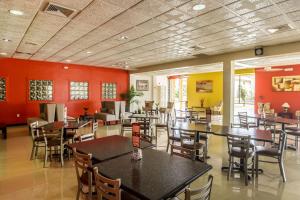 a restaurant with tables and chairs and red walls at Clarion Inn near McAllen Airport in McAllen