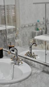 a bathroom sink with two faucets in front of a mirror at Al ladito de Sevilla in Bormujos +30 photos